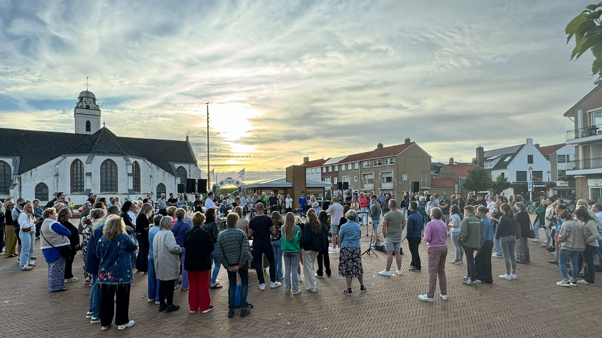Groep mensen zingt en aanbidt tijdens Paaspraise op het Andreasplein Katwijk